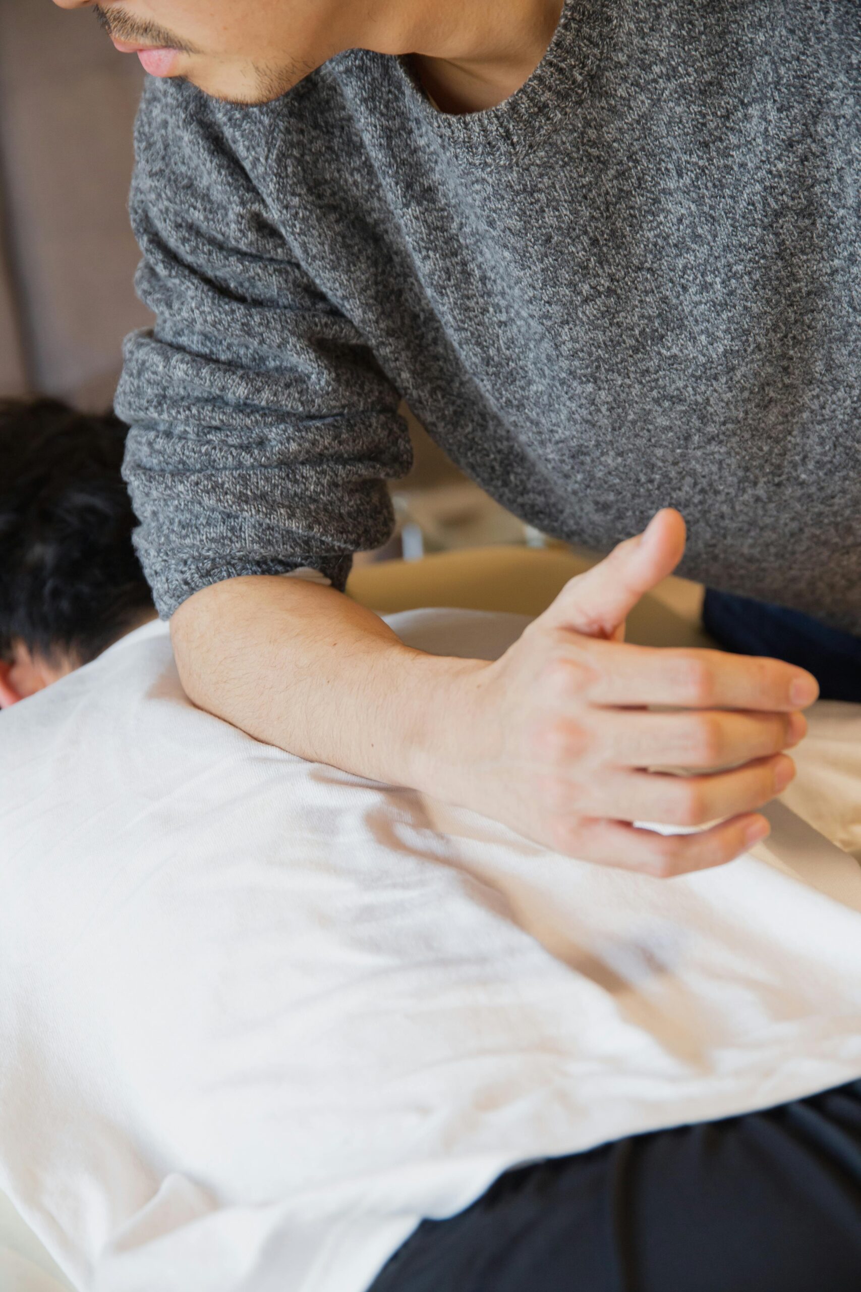Crop faceless male physiotherapist rubbing back of customer during manual therapy session in salon